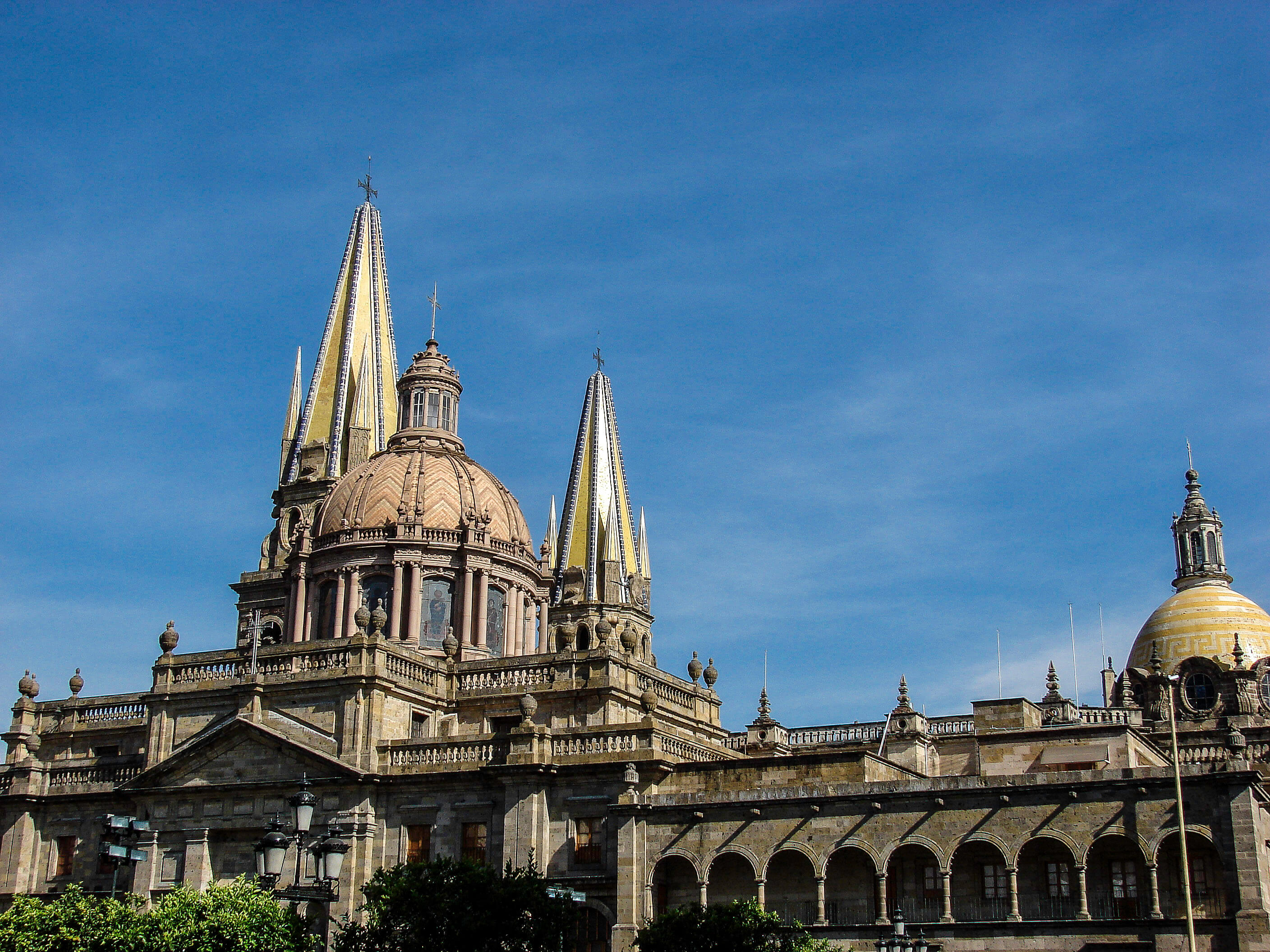 Iglesia colonial de dos torres y una cupula en medio con un cielo azul de fondo
